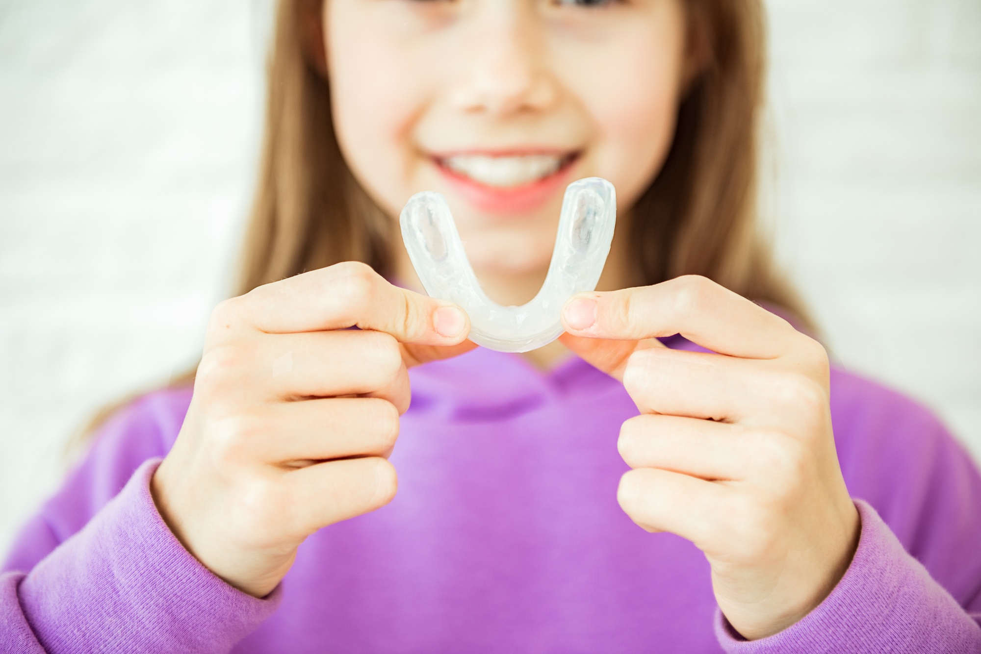 Smiling child girl shows myofunctional trainer. Help equalize the growing teeth and correct bite